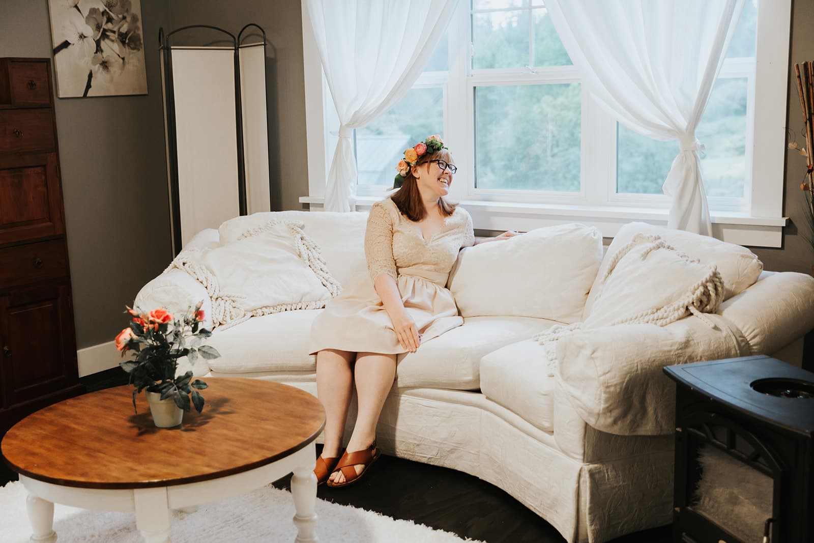 A bride in a flower crown relaxing on a white sofa in the light-filled bridal suite